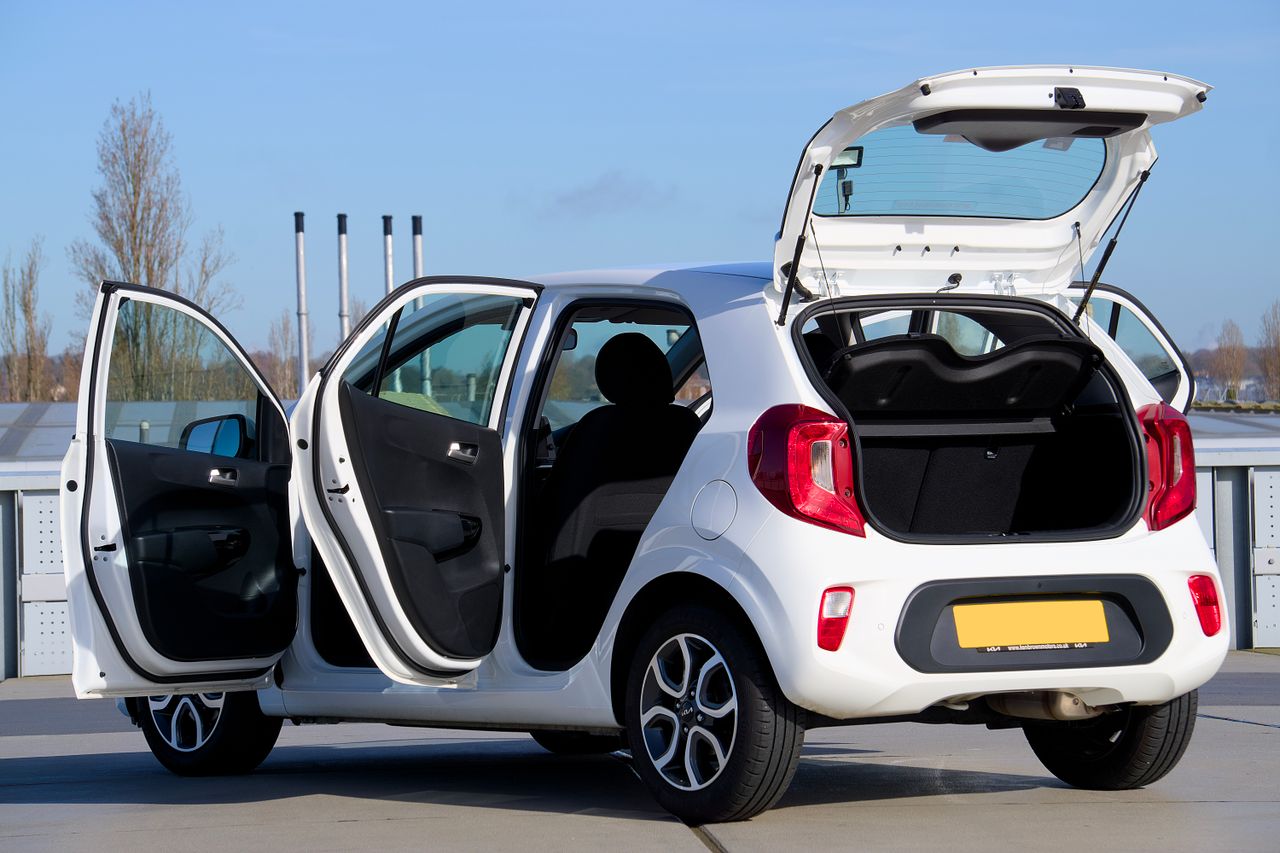 The Art of Drawing Readers In: Your attractive post title goes here A white compact car with open doors and trunk, photographed in an urban outdoor setting.
