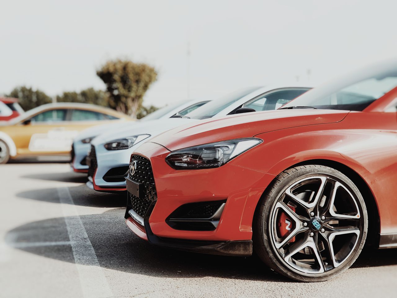 Mastering the First Impression: Your intriguing post title goes here A row of colorful cars parked outdoors in a sunny car park, highlighting the vehicles' design.